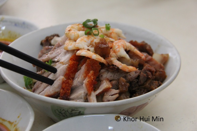 Bowl of extra ingredients consisting of shelled prawns, roast pork with crispy skin, char siew and bean sprouts. The sprouts are located right at the bottom of the bowl.